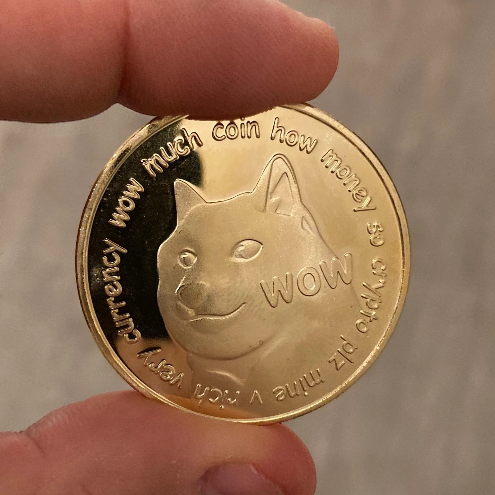 Front of the gold Dogecoin collectible coin with the Doge shiba inu face and WOW meme text